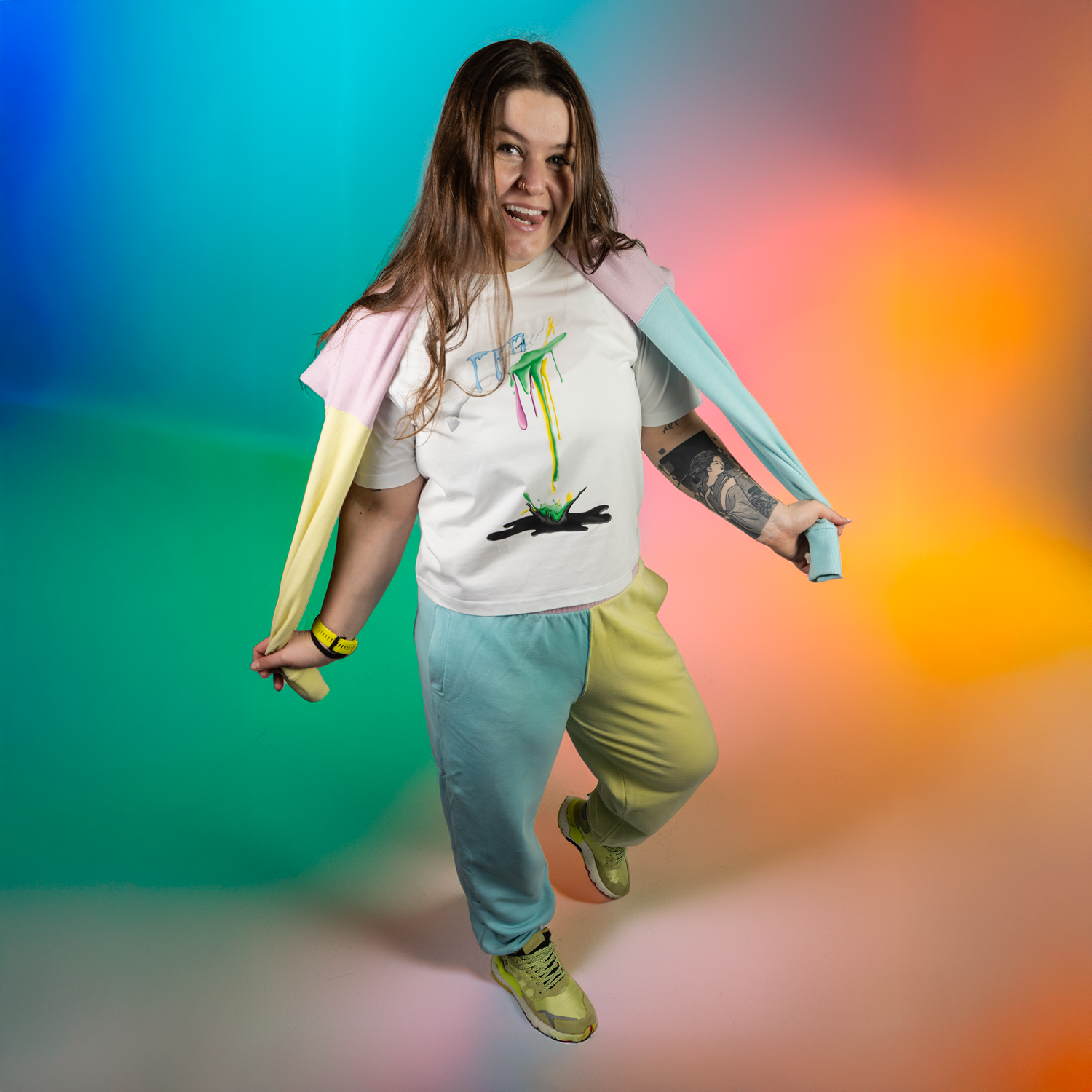 Person wearing a colourful outfit with a graphic design white t-shirt against a multi-coloured background