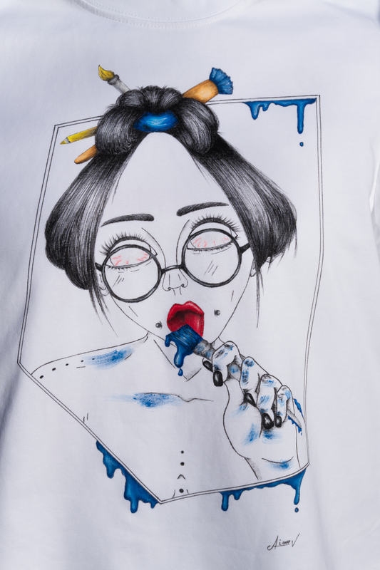 White t-shirt with a graphic design. The design is hand painted and shows a girl with round glasses, blue paint dripping and a brush. This is a close up.