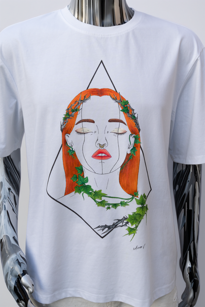 Mannequin wearing a white t-shirt with a graphic design on a plain background. The design is hand painted and shows a girl with orange hair, ivy leaves, and shimmery lips and eye makeup.