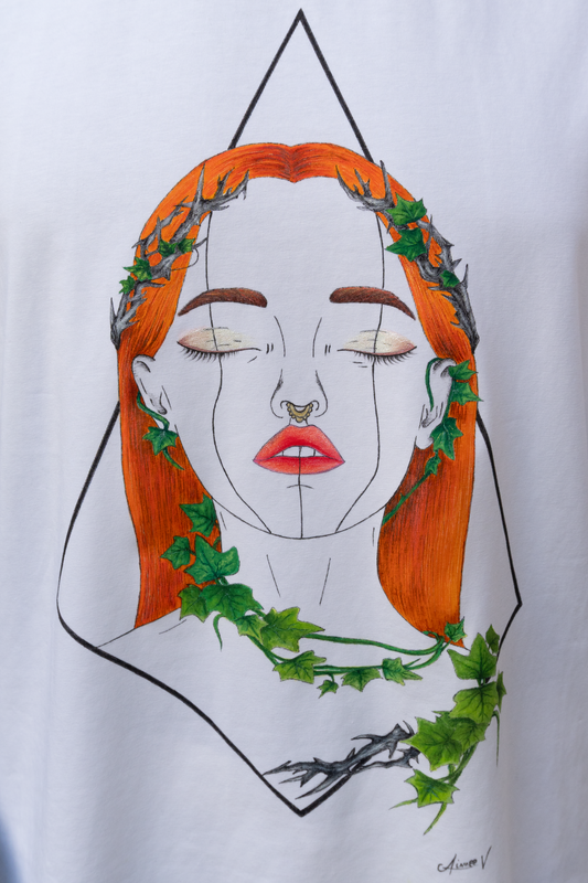 White t-shirt with a graphic design. The design is hand painted and shows a girl with orange hair, ivy leaves, shimmery makeup and a geometrical frame.