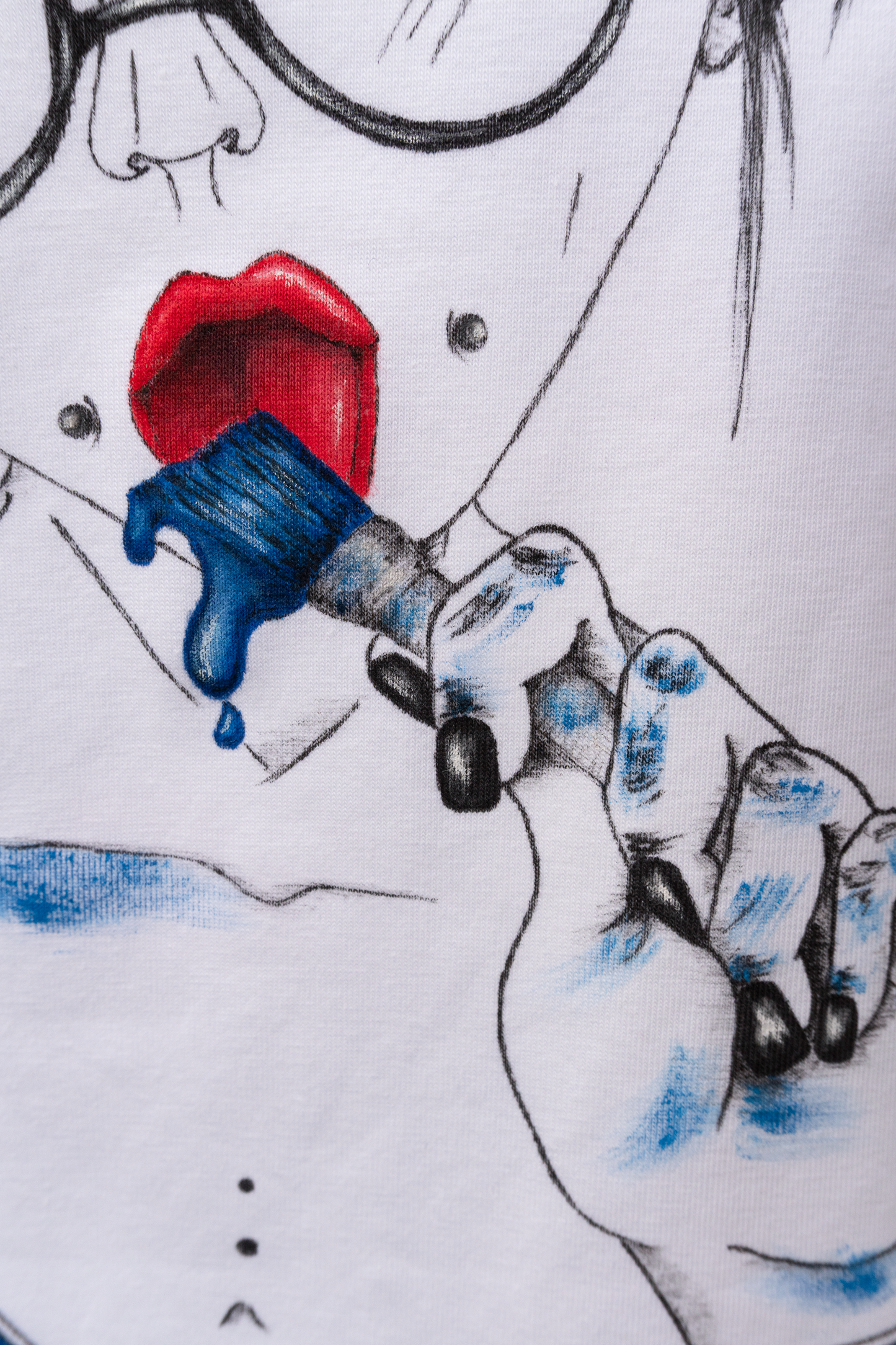 Close up of the hand and brush in the hand with blue paint dripping, of the girl with round glasses and blue dripping paint.