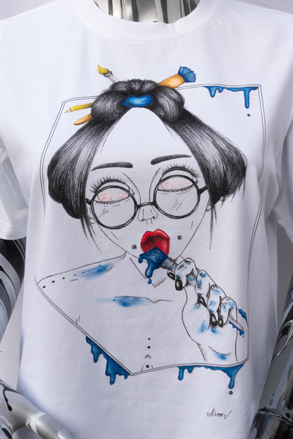 A close view of a mannequin wearing a white t-shirt with a graphic design on a plain background. The design is hand painted and shows a girl with round glasses, blue paint dripping and a brush.
