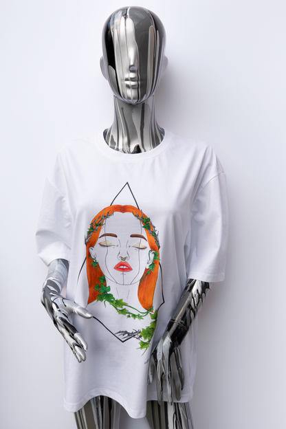 Female mannequin wearing a white t-shirt with a graphic design on a plain background. The design is hand painted and shows a girl with round glasses, blue paint dripping and a brush.