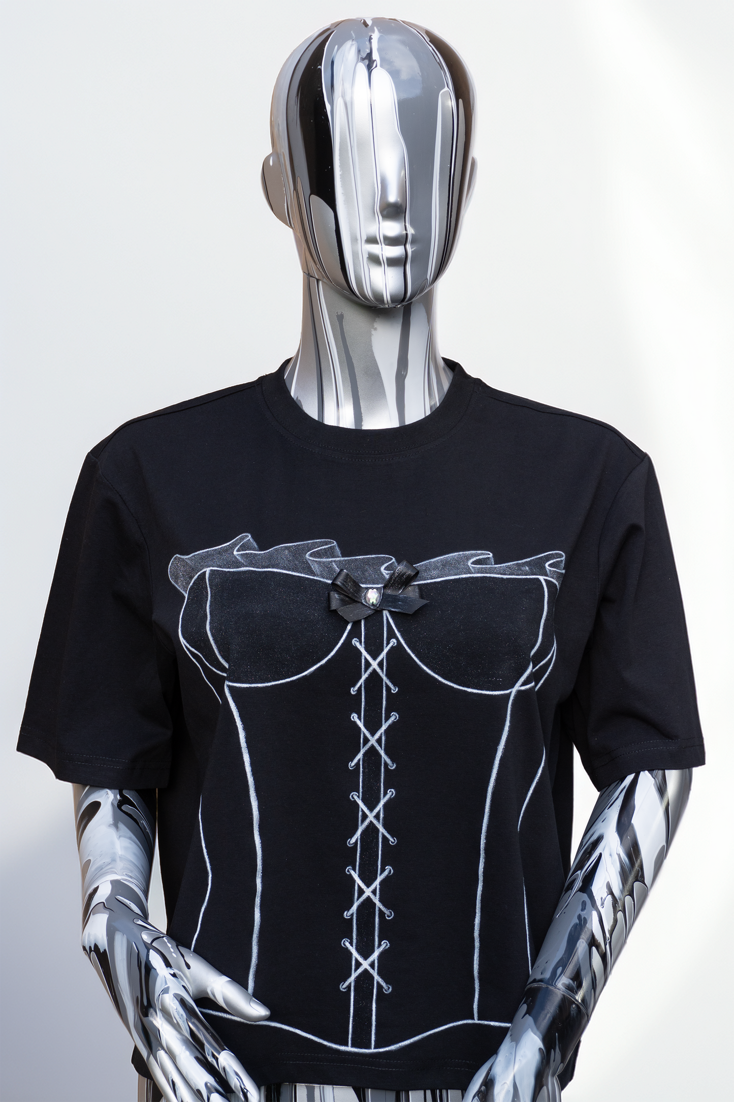 Female mannequin wearing a black t-shirt with white lace-up corset hand painted on the tshirt, with a hand sewed bow